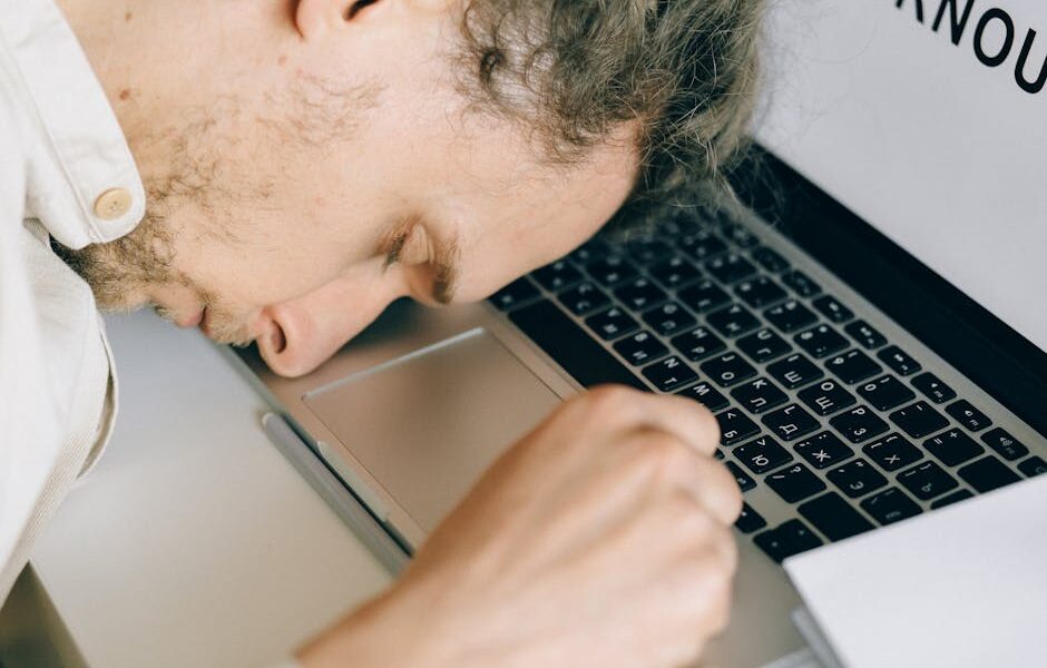 Mężczyzna śpiący z głową opartą na klawiaturze laptopa.